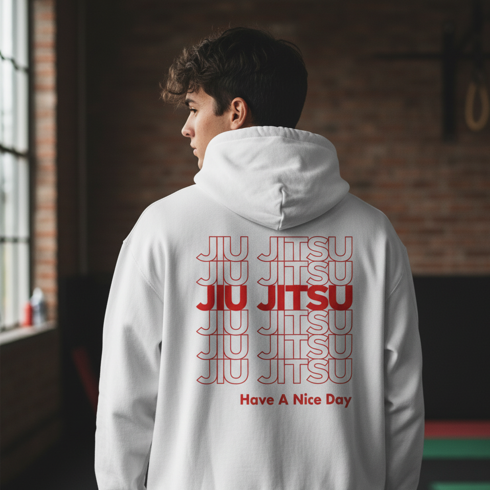 Person wearing a white hoodie with 'JIU JITSU' text on the back in a room with brick walls.